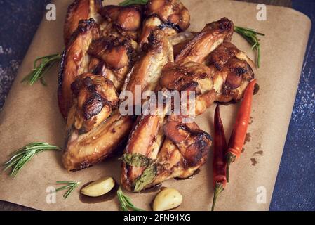 De délicieuses ailes de poulet frite se trouvent sur le plateau de service, décorées avec diverses épices, herbes et légumes. Mise au point sélective. Banque D'Images