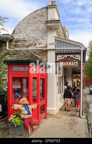 La ville historique d'Arrowtown, en Nouvelle-Zélande. Une pharmacie dans un bâtiment du XIXe siècle avec une ancienne cabine téléphonique rouge à l'extérieur Banque D'Images