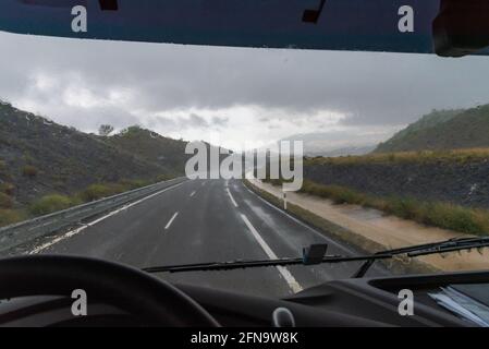 Vue sur l'autoroute depuis le siège conducteur d'un camion lors d'une lourde journée de pluie. Banque D'Images