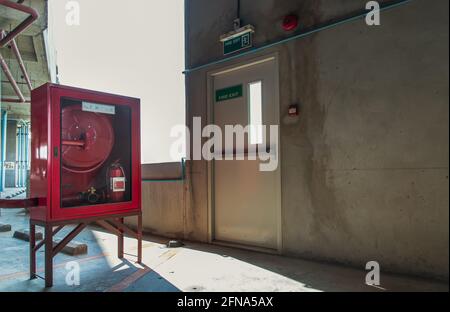 Porte de sortie de secours ou porte d'évacuation d'incendie avec panneau de sortie et armoire d'équipement de lutte contre l'incendie rouge dans un bâtiment de stationnement de voiture. La sécurité d'abord concept. Sélectif f Banque D'Images
