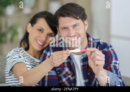 heureux couple caucasien portant une baguette de test de grossesse Banque D'Images