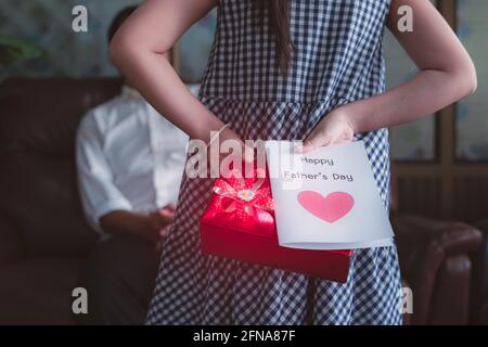 Petite fille fille tenant et cachant carte de voeux pour père Derrière le dos.concept de la fête des pères heureux Banque D'Images