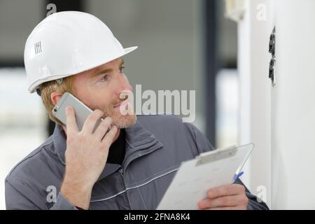 homme de métier tenant une planchette à pince et parlant sur un smartphone Banque D'Images