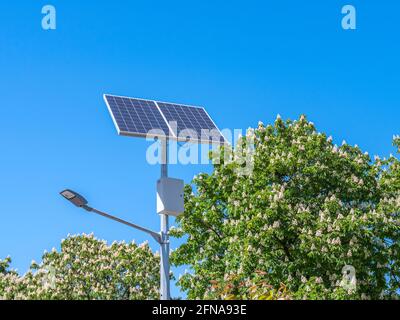 Une lampe de rue et un panneau solaire contre un ciel bleu. Banque D'Images