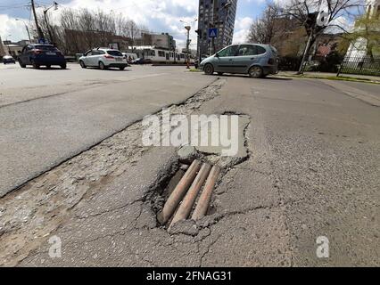 Bucarest, Roumanie - 08 avril 2021 : des tuyaux utilitaires sont visibles à la base d'une fosse d'asphalte dans une rue du centre de Bucarest. Banque D'Images