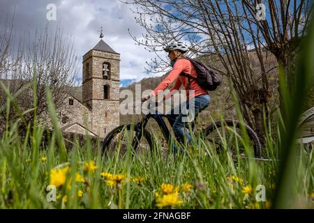 Femme à vélo et église romane de Sant Feliu, Barruera, Vall de Boí, Lleida, Catalogne, Espagne Banque D'Images