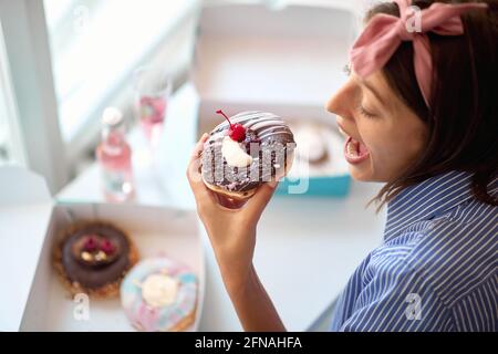 Bonne femme mangeant de délicieux beignets à la maison Banque D'Images