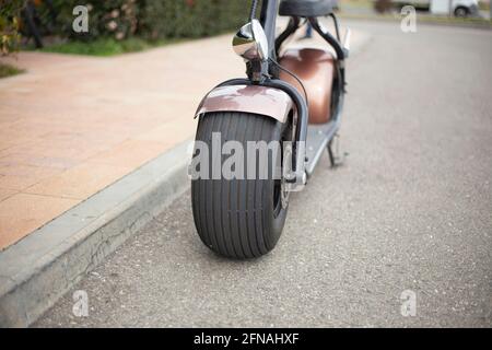 E-bike avec roues larges pour la conduite en ville. Mobylette de style rétro. Véhicules électriques garés. Moyen de se déplacer dans la rue. Location de scooter à la station. Banque D'Images