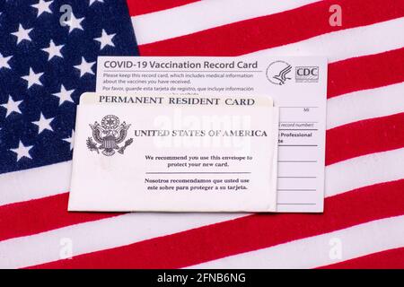 COVID-19 carte officielle de vaccination CDC, carte verte de résident permanent des États-Unis dans l'enveloppe sur le drapeau des États-Unis - San Jose, Californie Banque D'Images