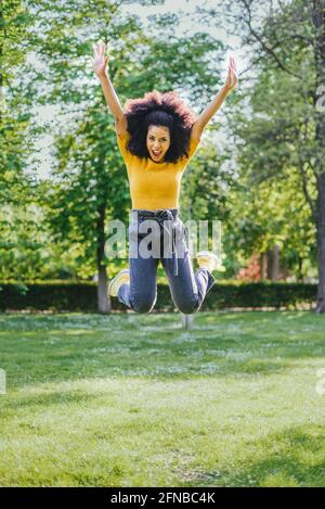 Jolie femme sautant volontiers dans un jardin. Corps entier. Banque D'Images