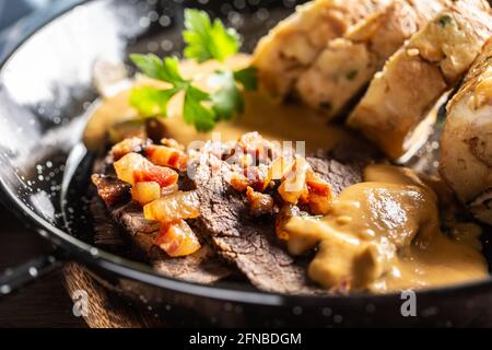 Un svickova typique de la cuisine tchèque avec des tranches de bœuf, une sauce à la crème, des boulettes de pain et des cubes de bacon frits. Banque D'Images
