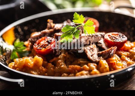 Sauce tomate gnocchi avec du bœuf sous-vide et des tomates fraîches servies dans une assiette foncée. Banque D'Images