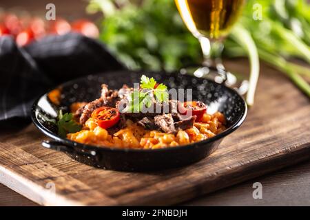 Sauce tomate gnocchi avec du bœuf sous-vide et des tomates fraîches servies dans une assiette foncée. Banque D'Images