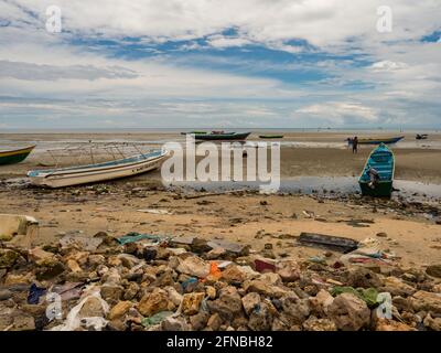 Kaimana, Arguni Bay, Indonésie - février 2018 : problème de pollution. Bateaux en bois et plein de déchets sur la plage à marée basse au port d'un petit Banque D'Images