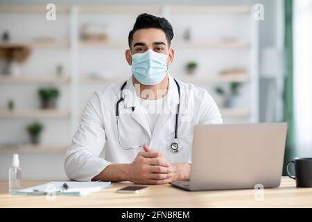 Médecin dans le masque facial travaillant sur l'ordinateur portable Banque D'Images