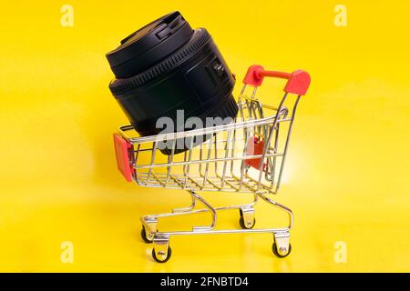 Objectif de la caméra dans le chariot de magasinage gros plan sur fond jaune Banque D'Images