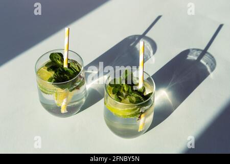 Deux boissons mojito avec pailles sur table bleue. Boissons rafraîchissantes froides. Longues ombres dures, vue de dessus Banque D'Images