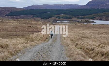 Femme solitaire marchant sur la route de la piste des îles Rannoch Moor Banque D'Images