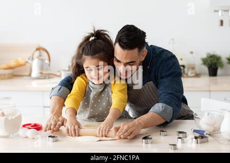 Une petite fille arabe et son père préparent une pâtisserie dans la cuisine ensemble Banque D'Images