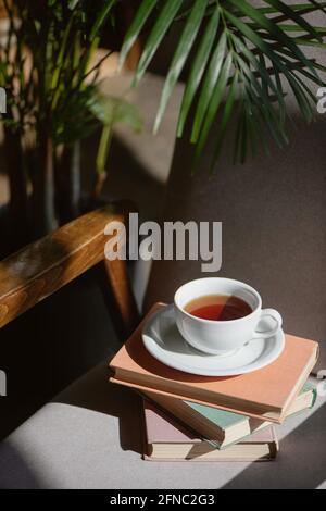 Pile de livres avec tasse de thé sur la chaise. Banque D'Images