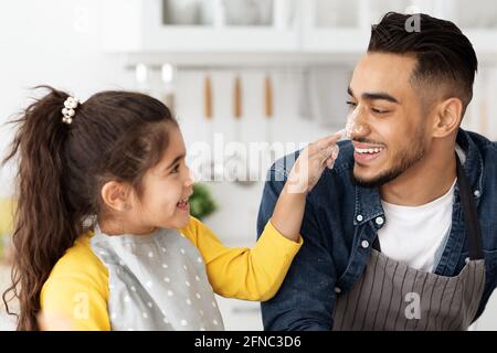 Adorable petite fille arabe s'amuser avec papa tout en cuisant Dans la cuisine Banque D'Images