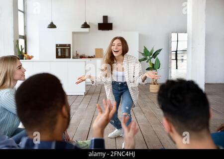 Groupe d'amis multiethniques jouant deviner qui jouent dans le moderne appartement Banque D'Images