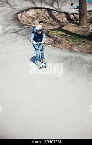 Un petit garçon fait un scooter sur les routes de la aire de jeux Banque D'Images