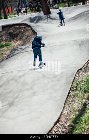 Un petit garçon fait un scooter sur les routes de la aire de jeux Banque D'Images