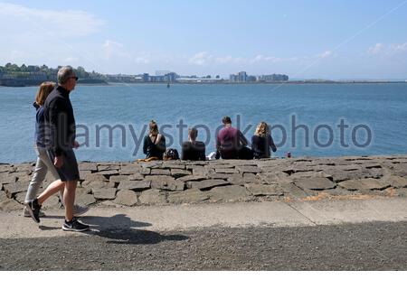 Édimbourg, Écosse, Royaume-Uni. 16 mai 2021. Les gens qui profitent de l'extérieur au bord de l'eau du port de Newhaven, dans un après-midi chaud et ensoleillé au printemps. Vue sur le quatrième estuaire vers le développement moderne à Granton. Crédit : Craig Brown/Alay Live News Banque D'Images