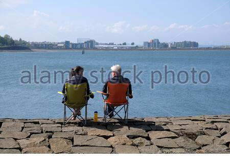 Édimbourg, Écosse, Royaume-Uni. 16 mai 2021. Les gens qui profitent de l'extérieur au bord de l'eau du port de Newhaven, dans un après-midi chaud et ensoleillé au printemps. Vue sur le quatrième estuaire vers le développement moderne à Granton. Crédit : Craig Brown/Alay Live News Banque D'Images