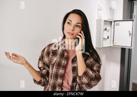 Jeune femme brunette expliquant son problème sur le téléphone portable pendant numéro d'appel Banque D'Images