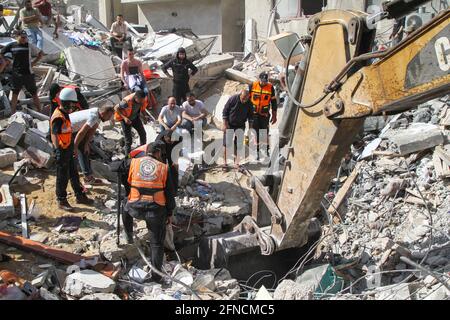 (210516) -- GAZA, le 16 mai 2021 (Xinhua) -- des membres de la défense civile palestinienne cherchent des corps ou des survivants en excavateur pour effacer les décombres de maisons détruites à la suite de frappes aériennes israéliennes dans la rue Al-Wahda, au milieu de la ville de Gaza, le 16 mai 2021. Les tensions entre Israël et les groupes militants de la bande de Gaza se sont poursuivies dimanche pour la septième journée consécutive, alors que le nombre de morts dans l'enclave côtière a grimpé à 181 et que 1,225 autres personnes ont été blessées, ont déclaré les responsables. Credit: Xinhua/Alay Live News Banque D'Images