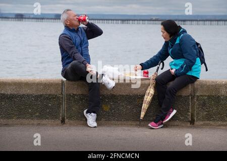 Southend on Sea Essex Angleterre Royaume-Uni 15 mai 2021 assis sur le mur de la mer manger des chips sur le front de mer de Southend. Banque D'Images