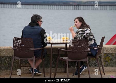 Southend on Sea Essex Angleterre Royaume-Uni 15 mai 2021 assis sur le mur de la mer manger des chips sur le front de mer de Southend. Banque D'Images