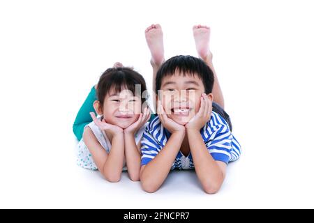 Enfants asiatiques couchés sur le sol. Les enfants chinois se sont contentés et souriants, isolés sur fond blanc. Conceptuel de l'amour des frères et sœurs. Happ Banque D'Images