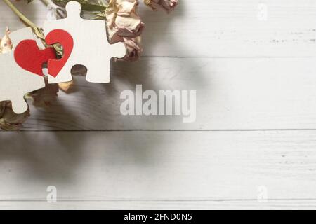 Le cœur rouge est dessiné sur les pièces du puzzle en bois qui se trouvent les unes à côté des autres sur fond blanc. Concept d'amour. Banque D'Images