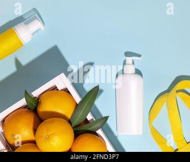 Composition cosmétique avec agrumes dans une boîte en bois, un sac en coton et une bouteille de cosmétiques sur fond bleu. Maquette de cosmétiques d'été Banque D'Images