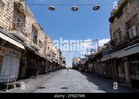 Une femme marchant dans la rue principale du marché de Mahane Yehuda le matin du Sabbat avec tous les magasins fermés. Banque D'Images