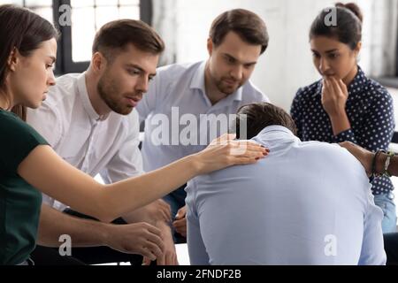 Groupe diversifié offrant confort et soutien à un ami contrarié Banque D'Images