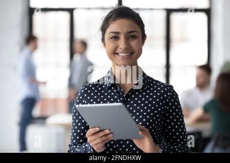 Portrait d'un employé du millénaire indien heureux utilisant une tablette au bureau Banque D'Images