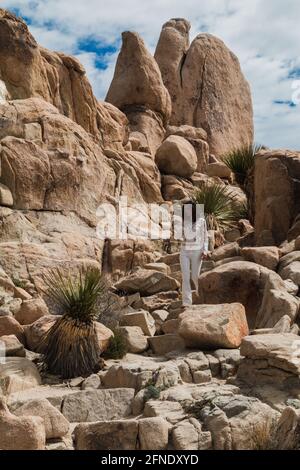 Une femme vêtue de blanc, marchant à travers des marches rocheuses lors d'une randonnée à Joshua Tree Banque D'Images