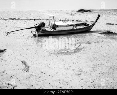 Bateau de pêche à longue queue en bois de villageois vides dans la boue de plage de style noir et blanc avec espace de copie. Style de vie des pêcheurs thaïlandais. Banque D'Images