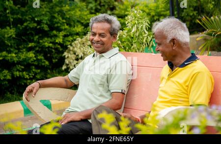 Heureux souriant des amis âgés ayant un peu de bon temps pendant la soirée au parc en se souvenant de vieux souvenirs - concept de la relaxation de personnes âgées, l'amitié et Banque D'Images