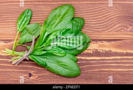 Bouquet de jeunes épinards frais et verts avec corde sur table en bois, vue sur le dessus Banque D'Images