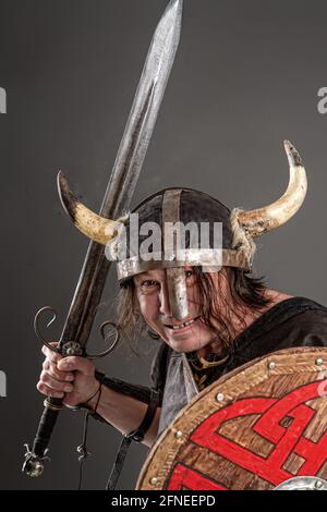 chevalier comique dans un casque à cornes avec un bouclier et épée sur fond sombre Banque D'Images