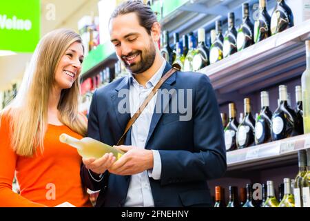 La sélection de vin en supermarché Couple Banque D'Images