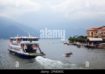 Vue sombre et brumeuse du matin sur le port et le village de Bellagio, petite ville sur le lac de Côme, en Italie, avec une eau calme et un ferry en bateau Banque D'Images