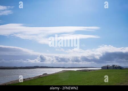 Ferme en Islande sur un pâturage bordant l'eau sous ciel d'été rétroéclairé bleu Banque D'Images