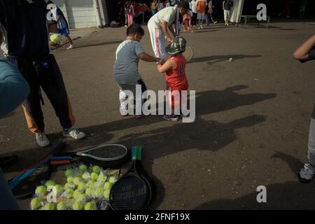 Parents et enfants jouant à un sport de loisir en heurtant une balle de tennis attachée à l'extrémité d'une corde qui est ancrée à une pierre, à l'extérieur du stade principal Senayan (stade Gelora Bung Karno) à Jakarta, en Indonésie. Banque D'Images