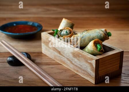 Rouleaux de printemps vietnamiens avec sauce douce. Rouleaux de printemps chinois frits avec sauce Chili douce. Collations asiatiques populaires auprès des thaïlandais et chinois. Servi dans des boîtes décoratives en bois. Banque D'Images